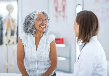 Une patiente senior souriante qui discute avec sa praticienne au cabinet