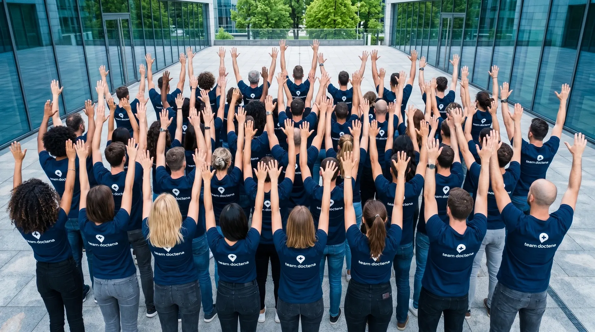The Doctena team seen from behind, wearing branded polos with the Doctena pin and logo