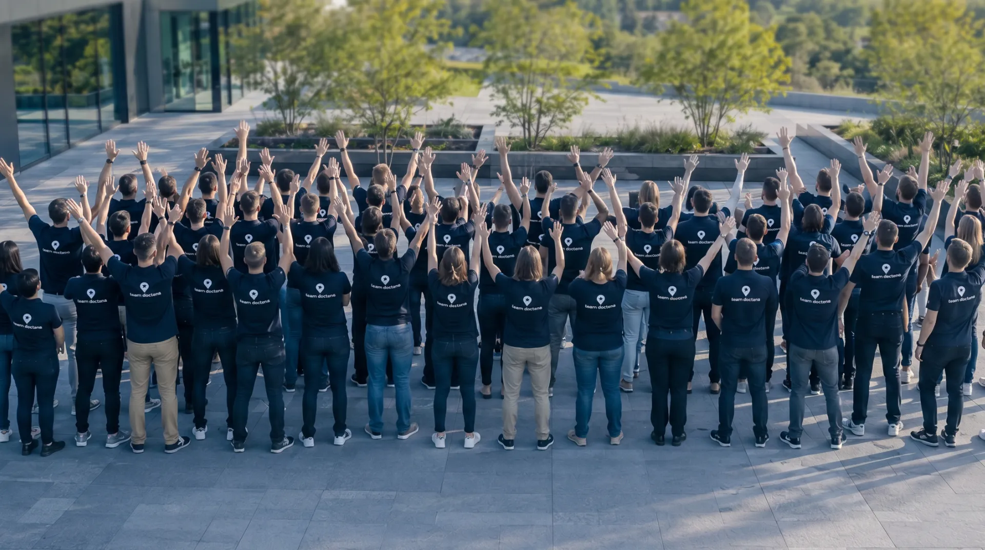 The Doctena team seen from behind, wearing branded polos with the Doctena pin and logo